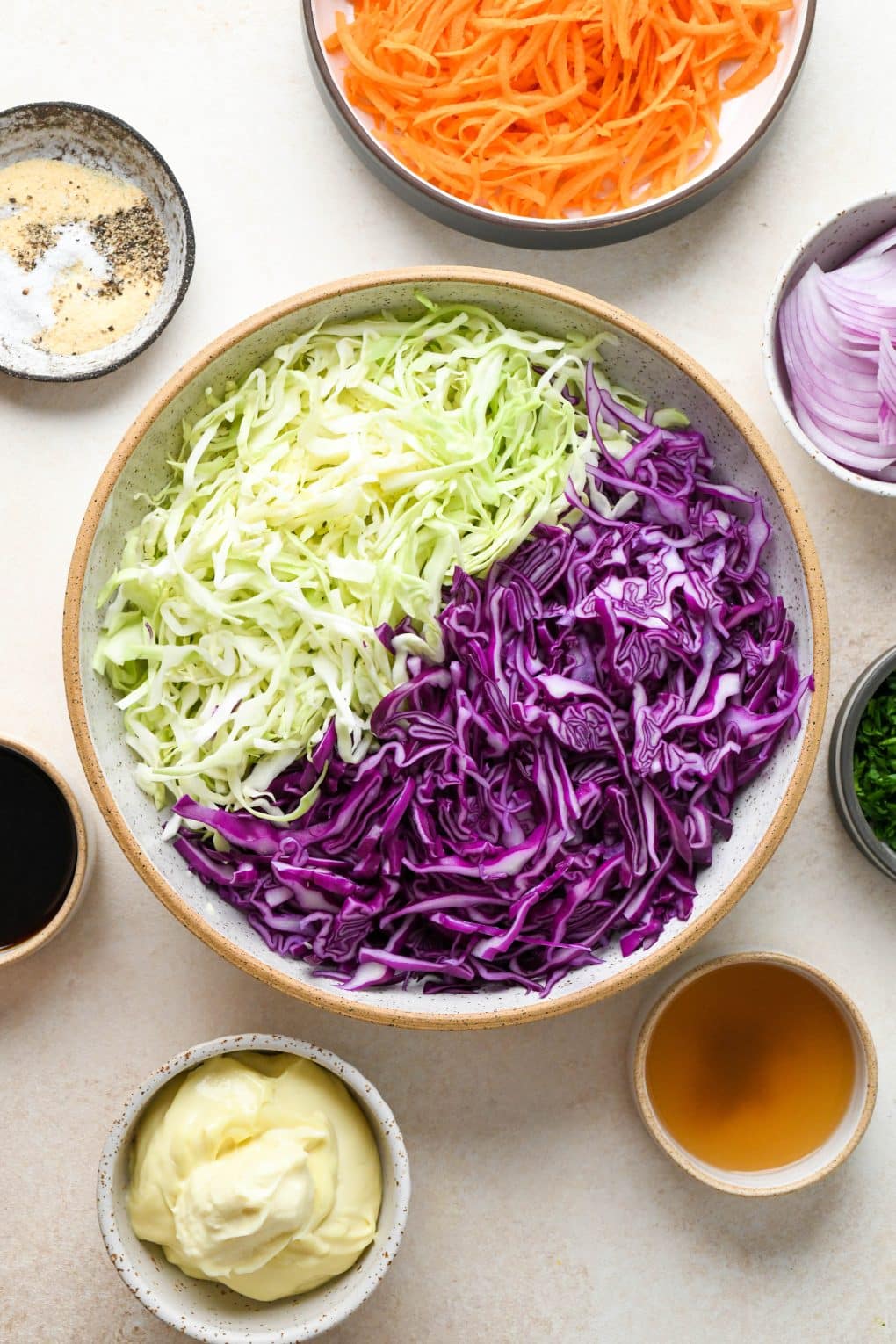 Ingredients for Whole30 coleslaw in various sized ceramics on a light cream colored background.