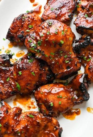 Baked bbq chicken thighs on a large white oval platter.