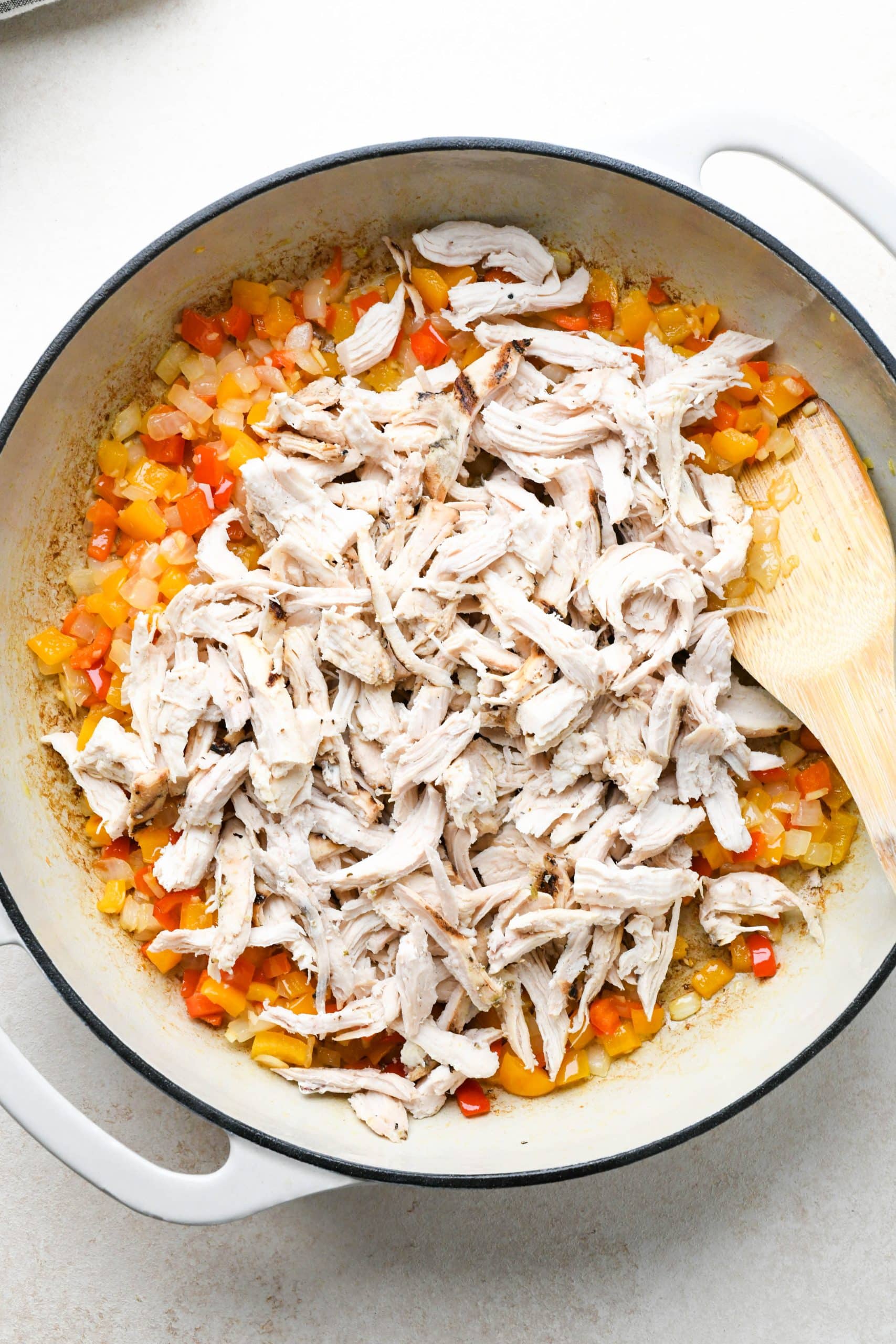 How to make buffalo chicken pasta: Shredded chicken added to the skillet with cooked veggies. 