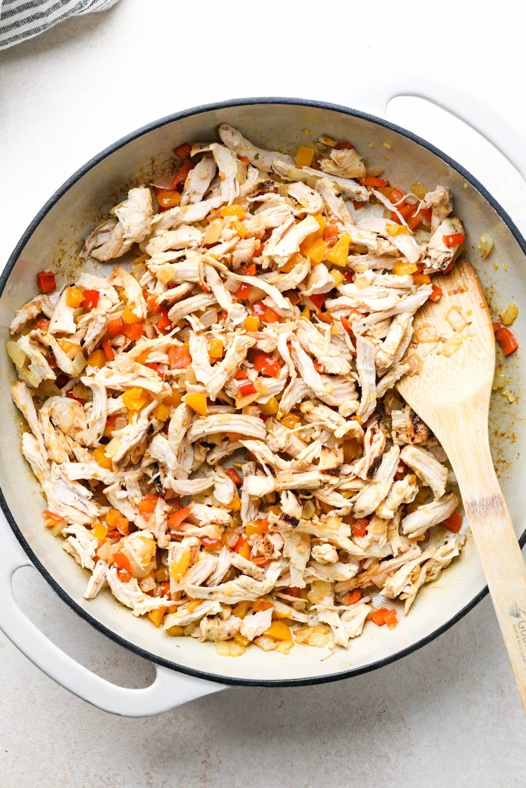 How to make buffalo chicken pasta: Chicken tossed together with cooked veggies in skillet.