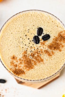 Overhead view of a creamy pumpkin spice espresso martini, garnished with cinnamon and 3 coffee beans.