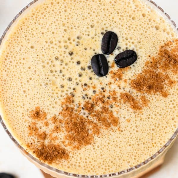 Overhead view of a creamy pumpkin spice espresso martini, garnished with cinnamon and 3 coffee beans.
