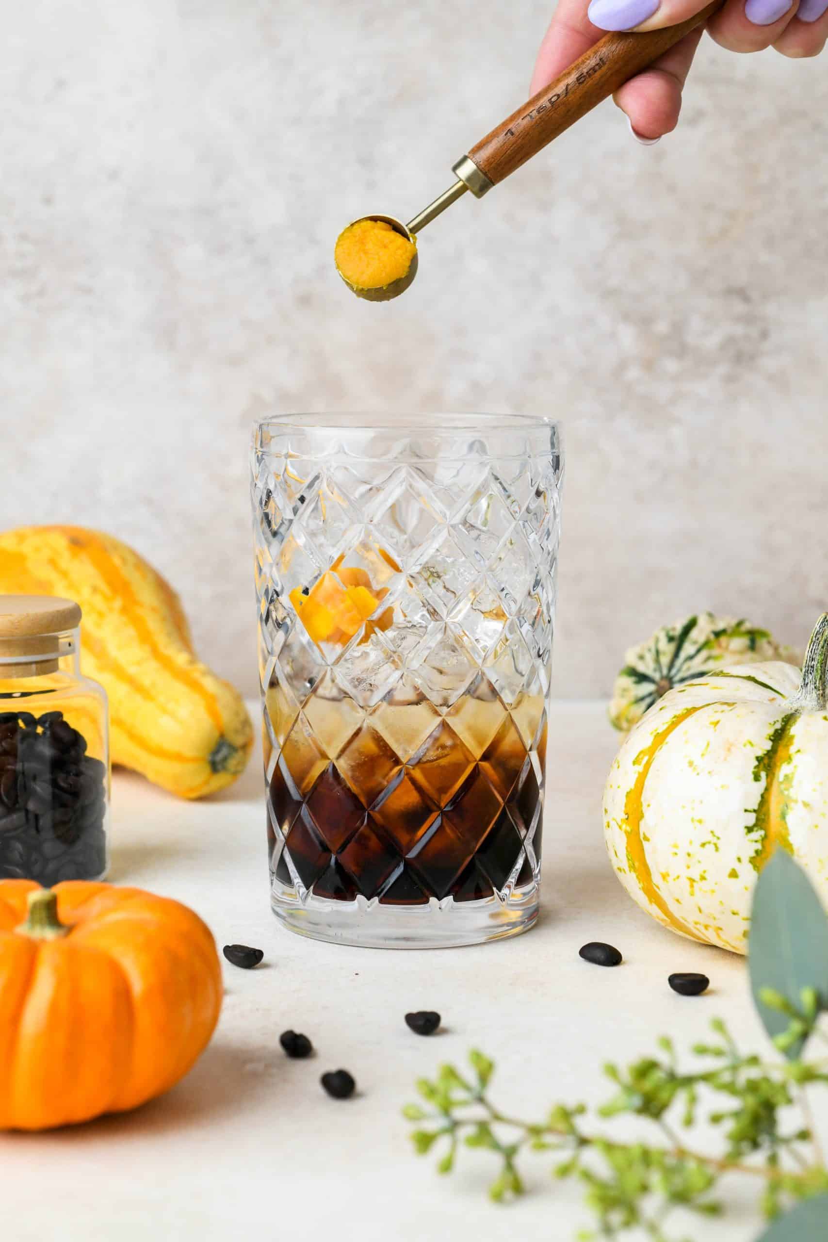 How to make a pumpkin spice espresso martini: Adding pumpkin puree to cocktail shaker with ice.