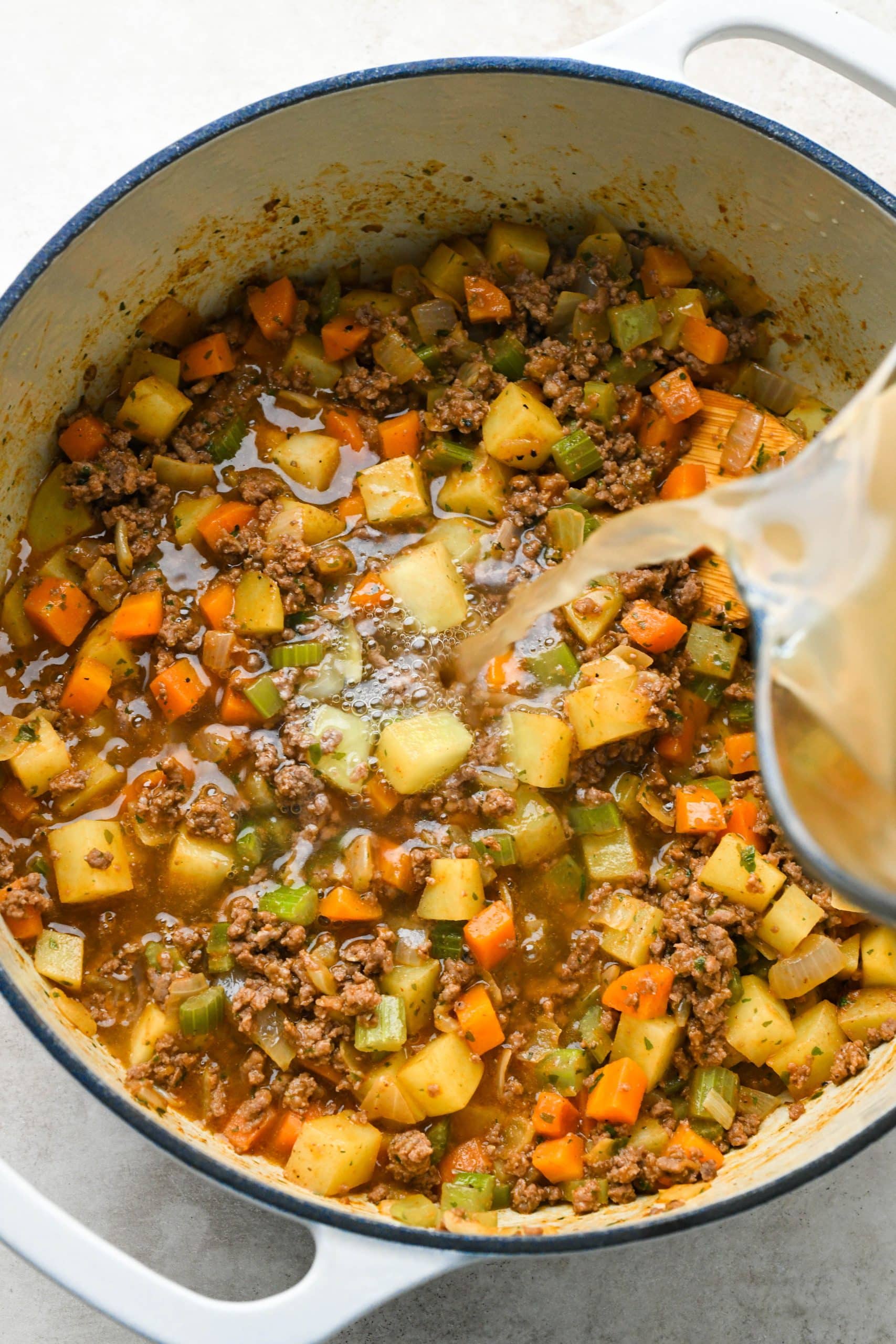 How to make shepherds pie soup: Pouring broth into the soup pot.