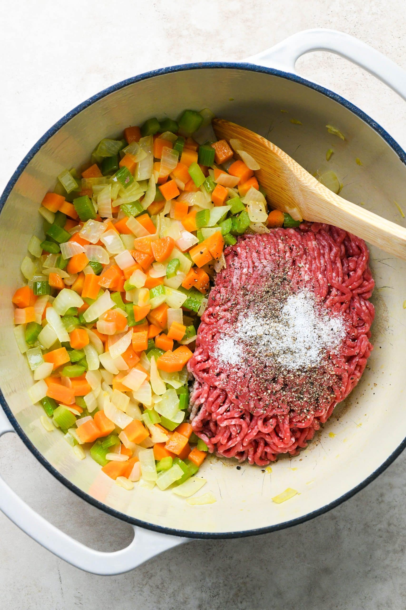 How to make shepherds pie soup: Adding ground beef with salt and pepper to the soup pot.