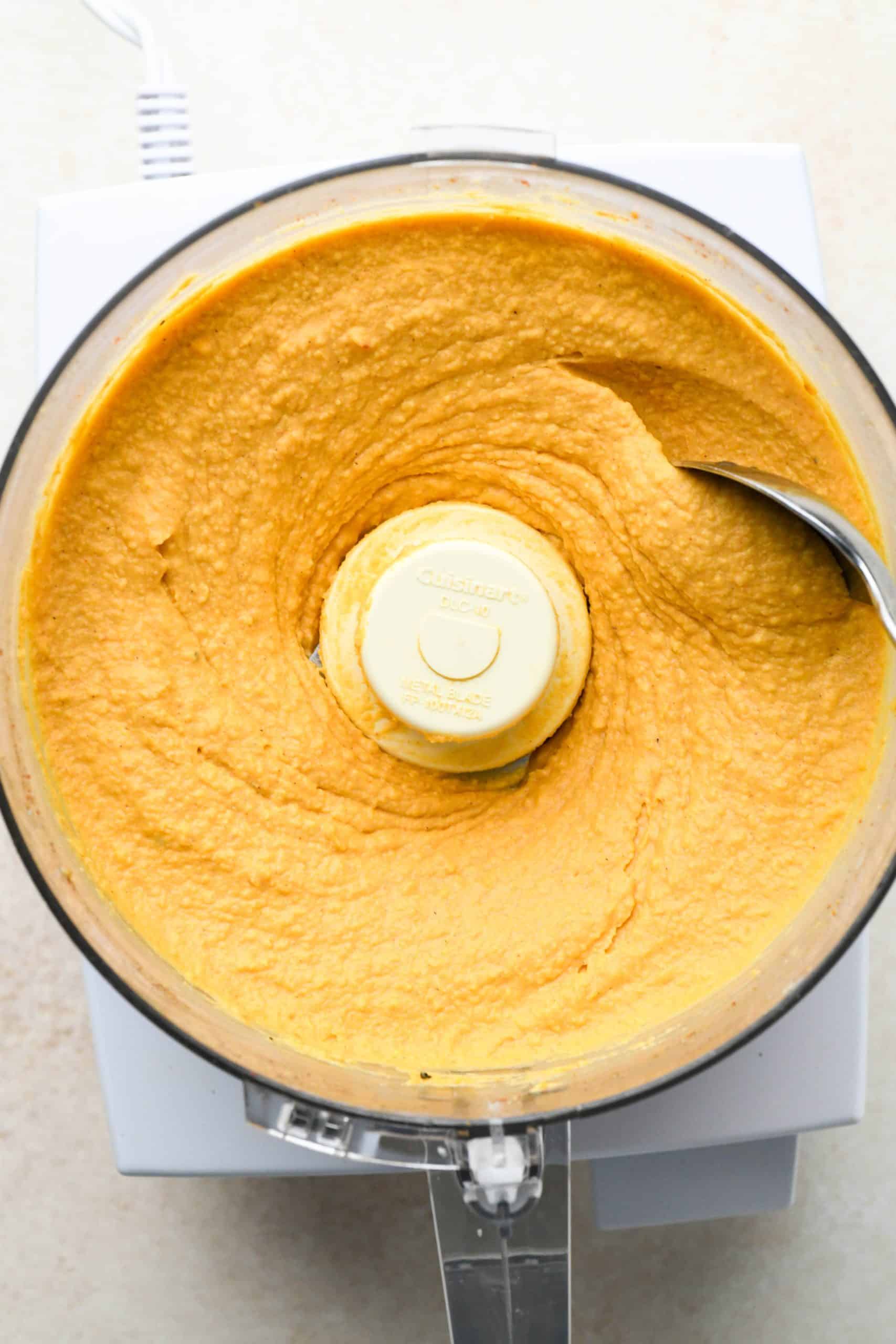 How to make Sweet Potato Hummus: Smooth and creamy hummus blended together in food processor container.