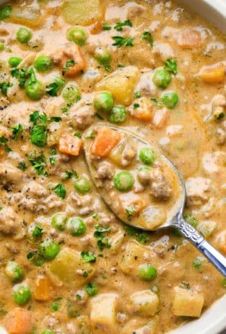 Close up of a spoon dipping into a thick and creamy bowl of dairy free shepherds pie soup.
