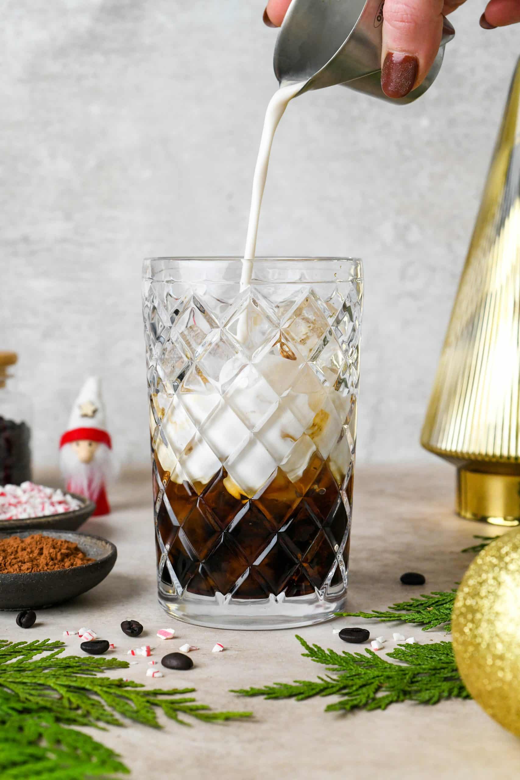 How to make Peppermint Mocha Espresso Martinis: Adding the creamer to an etched glass cocktail shaker filled with ice.