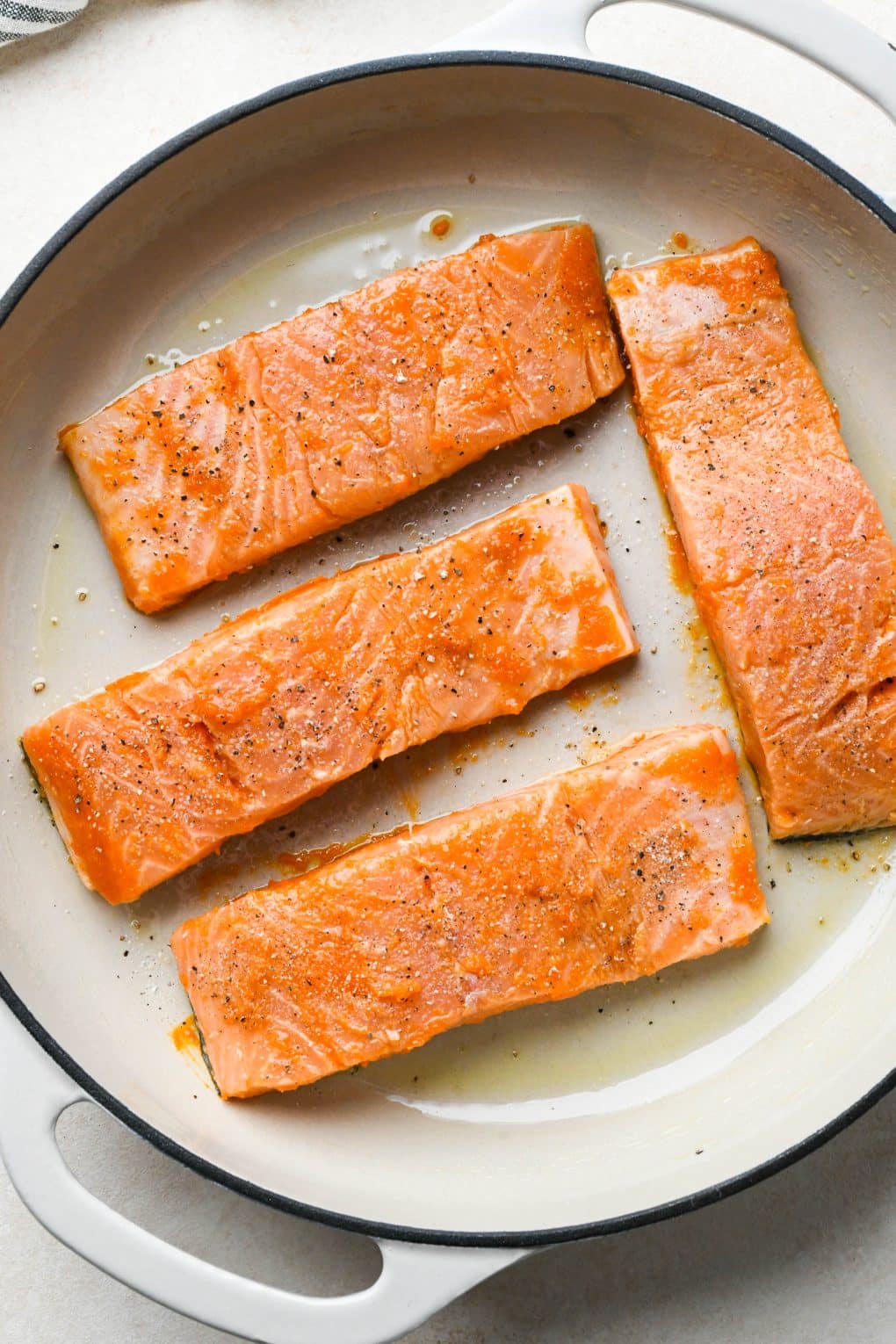 How to make baked buffalo salmon: Marinated salmon fillets in a round casserole skillet topped with salt and pepper - before baking.