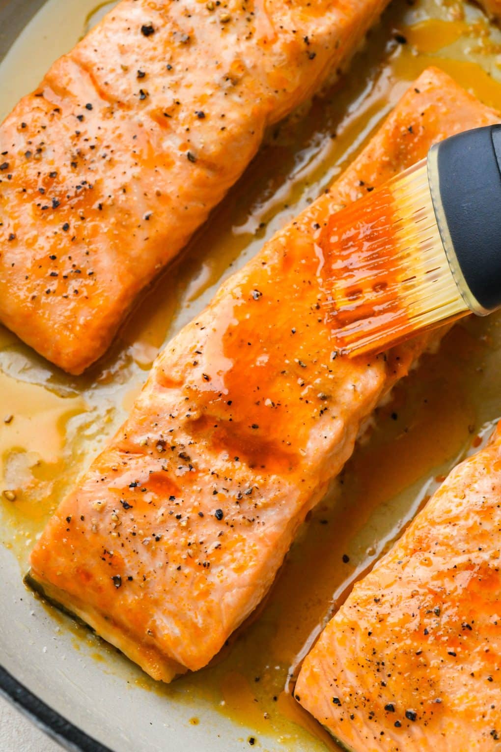 How to make baked buffalo salmon: Brushing extra buffalo sauce over partially baked salmon fillets.