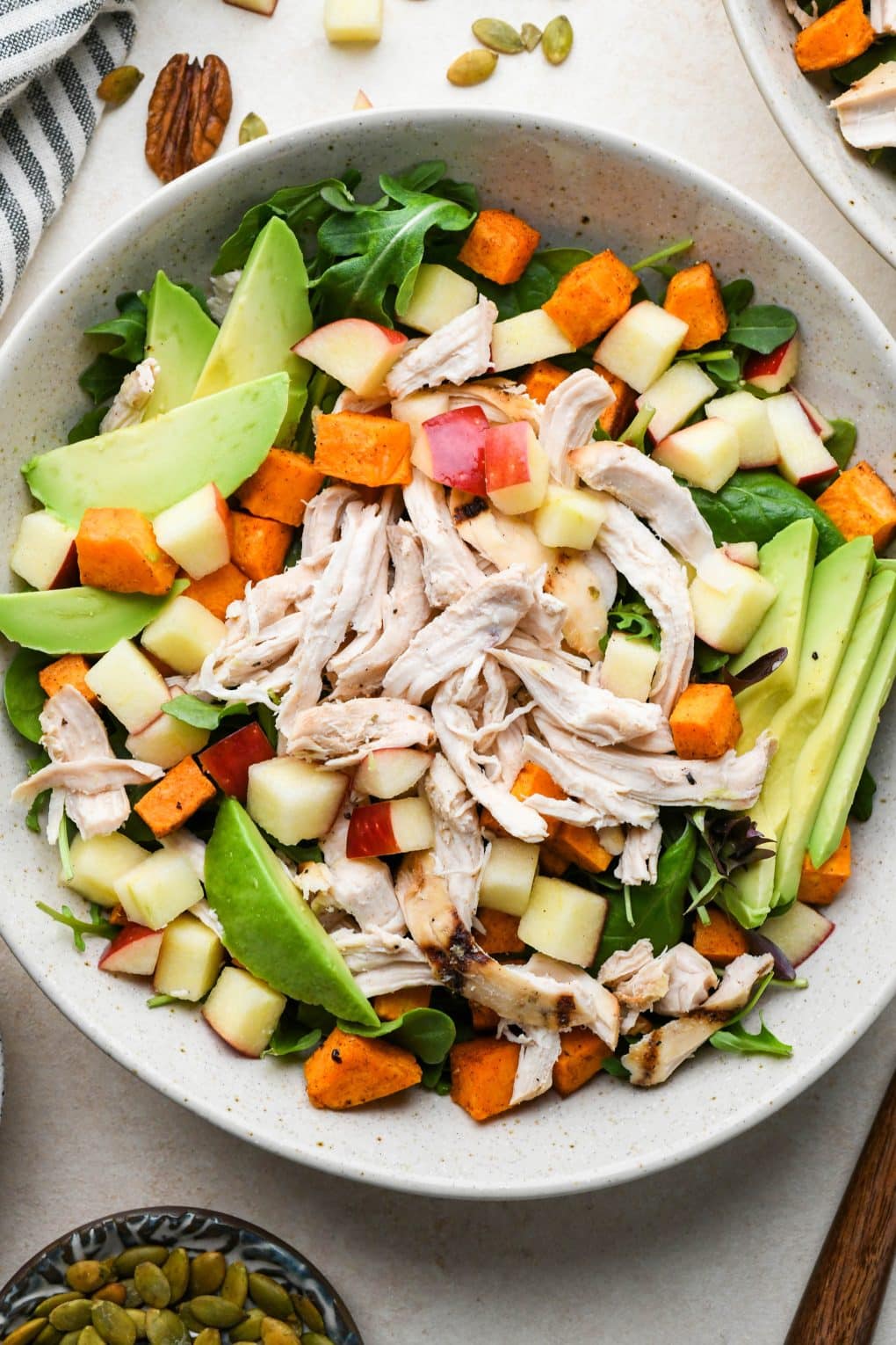 How to make Winter Chicken Salad: Salad ingredients assembled in a bowl before adding dressing, nuts, and seeds.