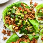 How to make Pork Lettuce Wraps: Ground pork mixture piled into a lettuce cup topped with cucumber salad, chopped cashews, and chopped cilantro.