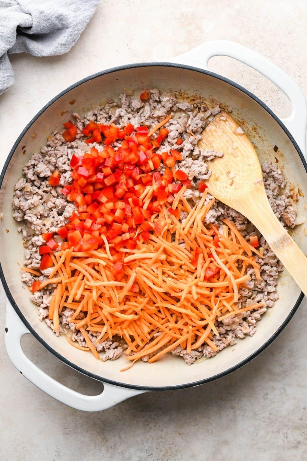 How to make Pork Lettuce Wraps: Shredded carrot and diced bell pepper added to skillet with cooked ground pork and shallots.