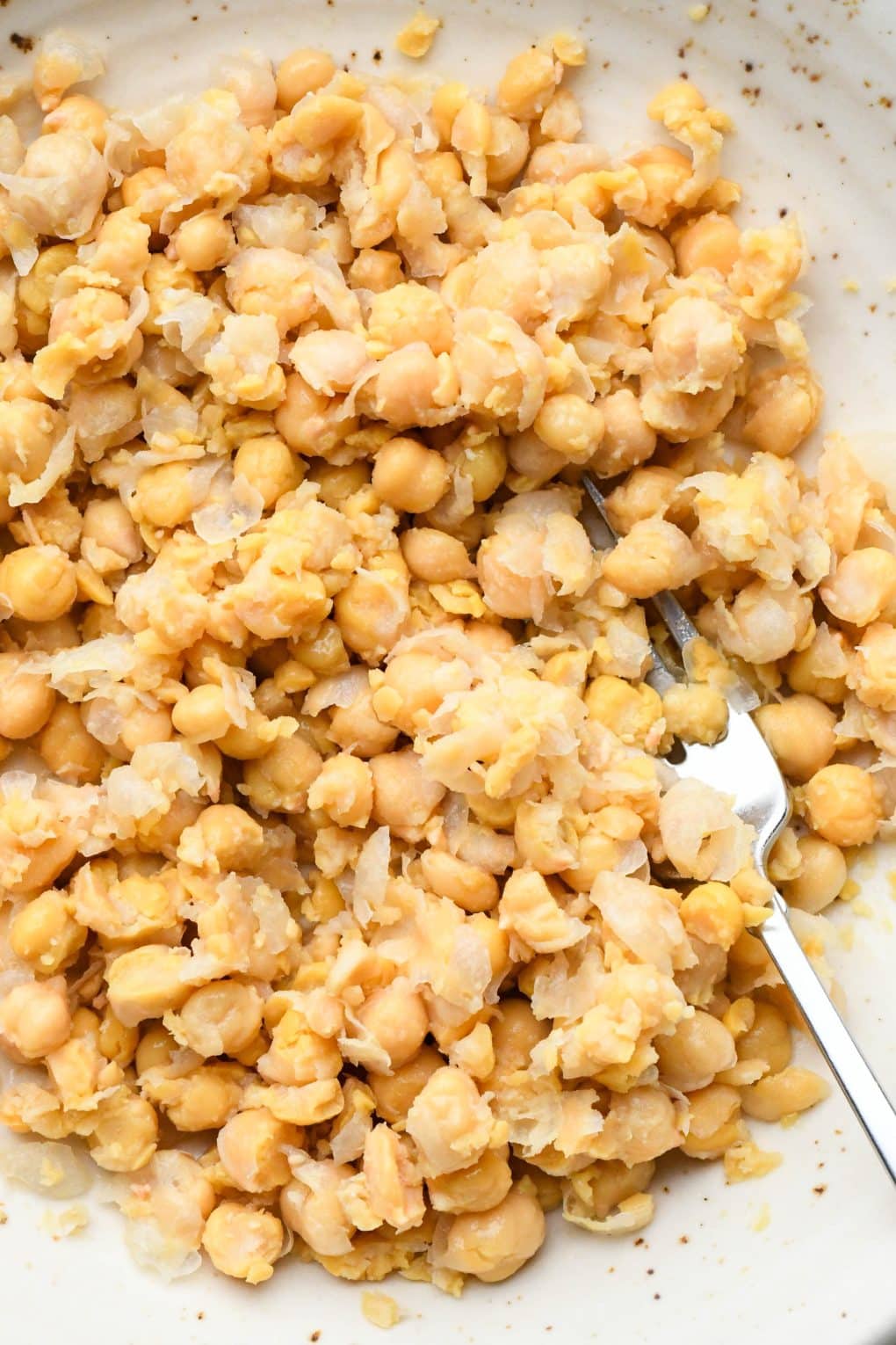 Up close image of the smashed chickpeas to show the rough texture, with some chickpeas left whole.