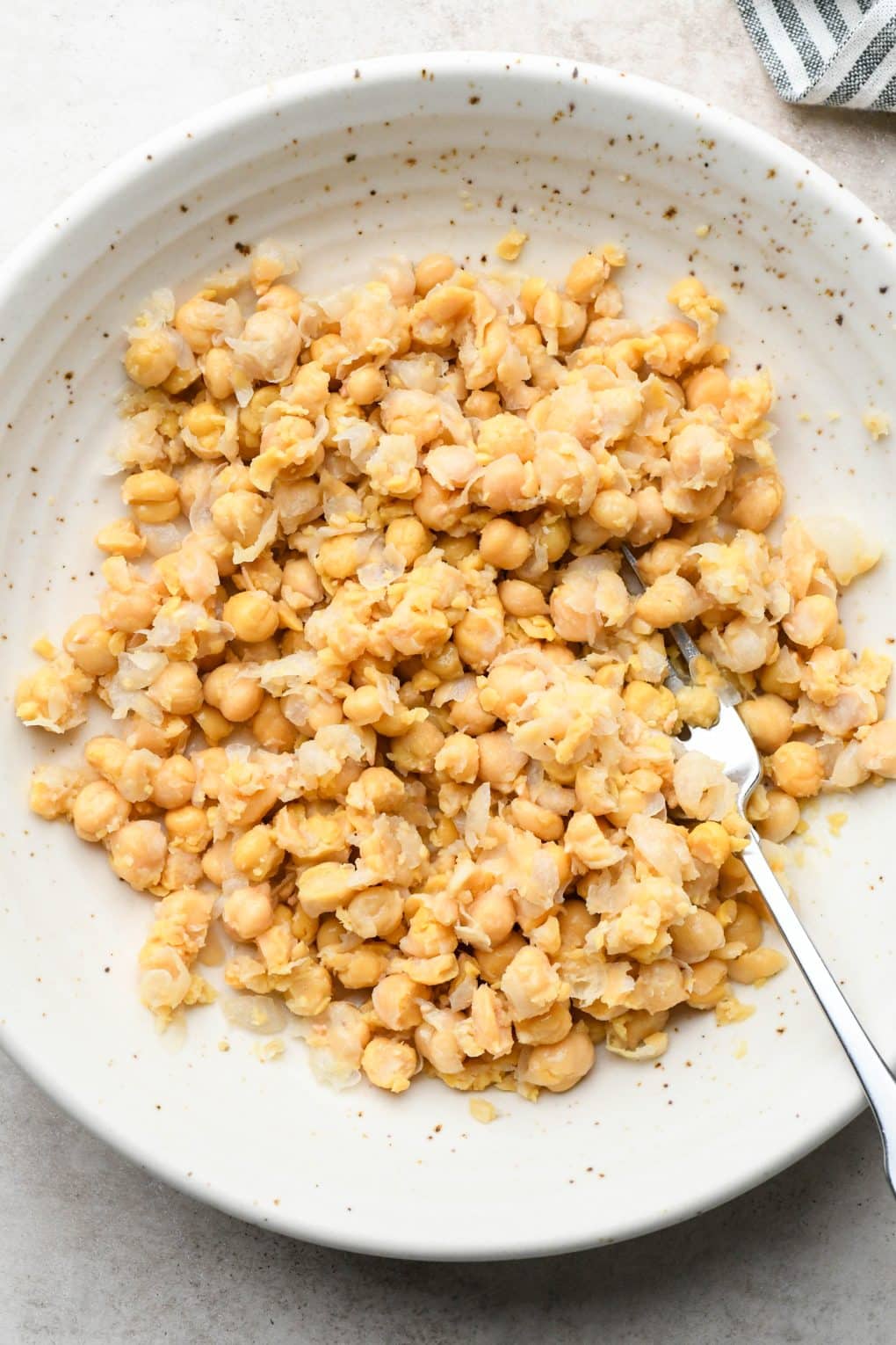 How to make smashed chickpea salad: Chickpeas roughly mashed in a large shallow bowl.