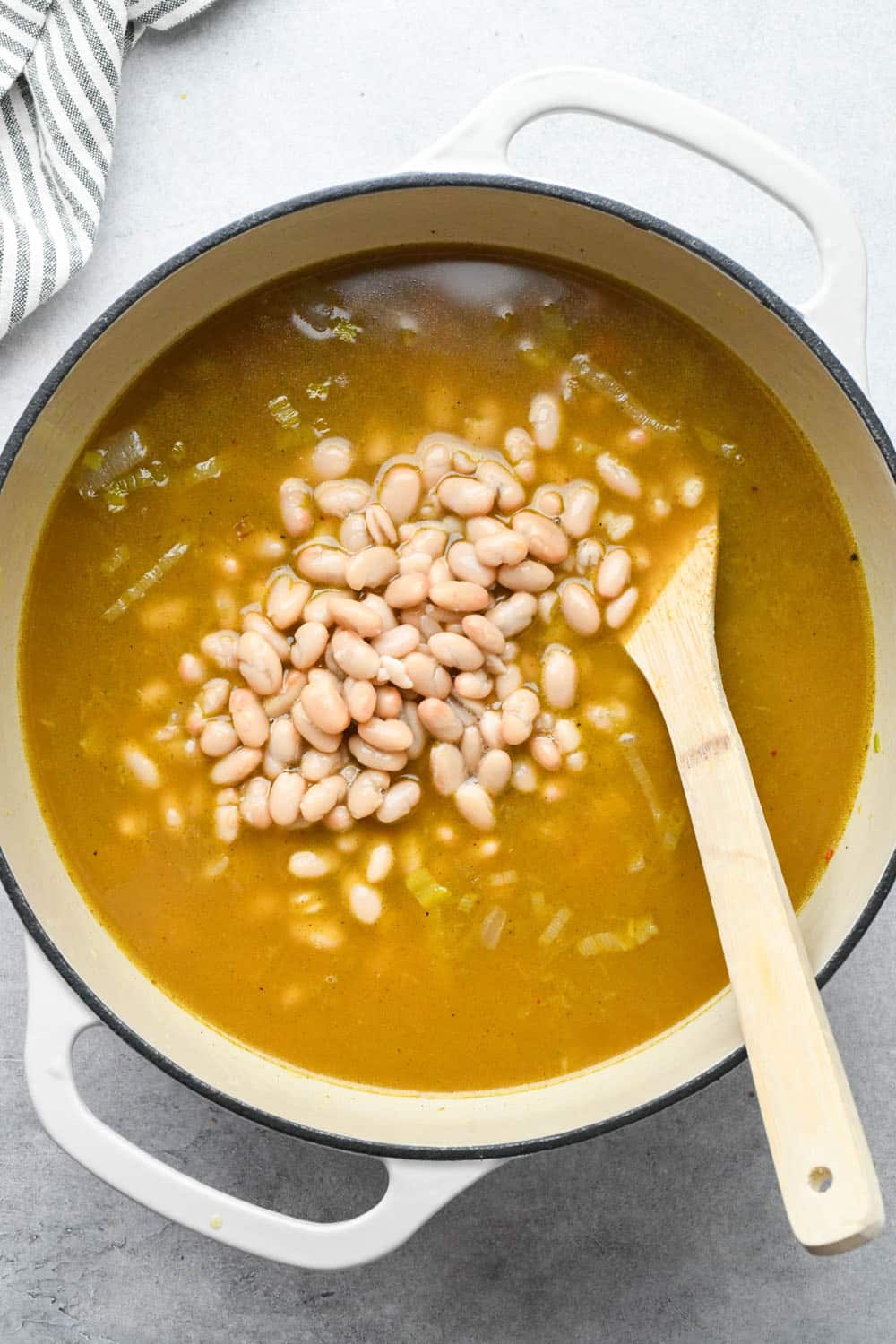How to make White Bean and Kale Soup: Beans added to soup pot with broth and veggies.