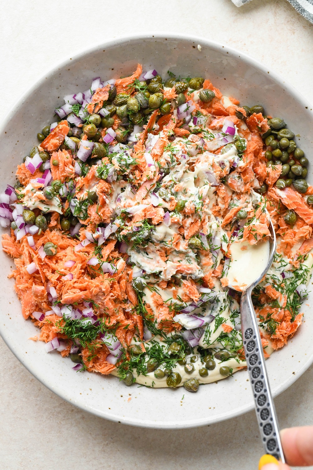 How to make dairy free smoked salmon dip: Mixing the smoked salmon, capers, dill, and red onion into the cashew cream base.