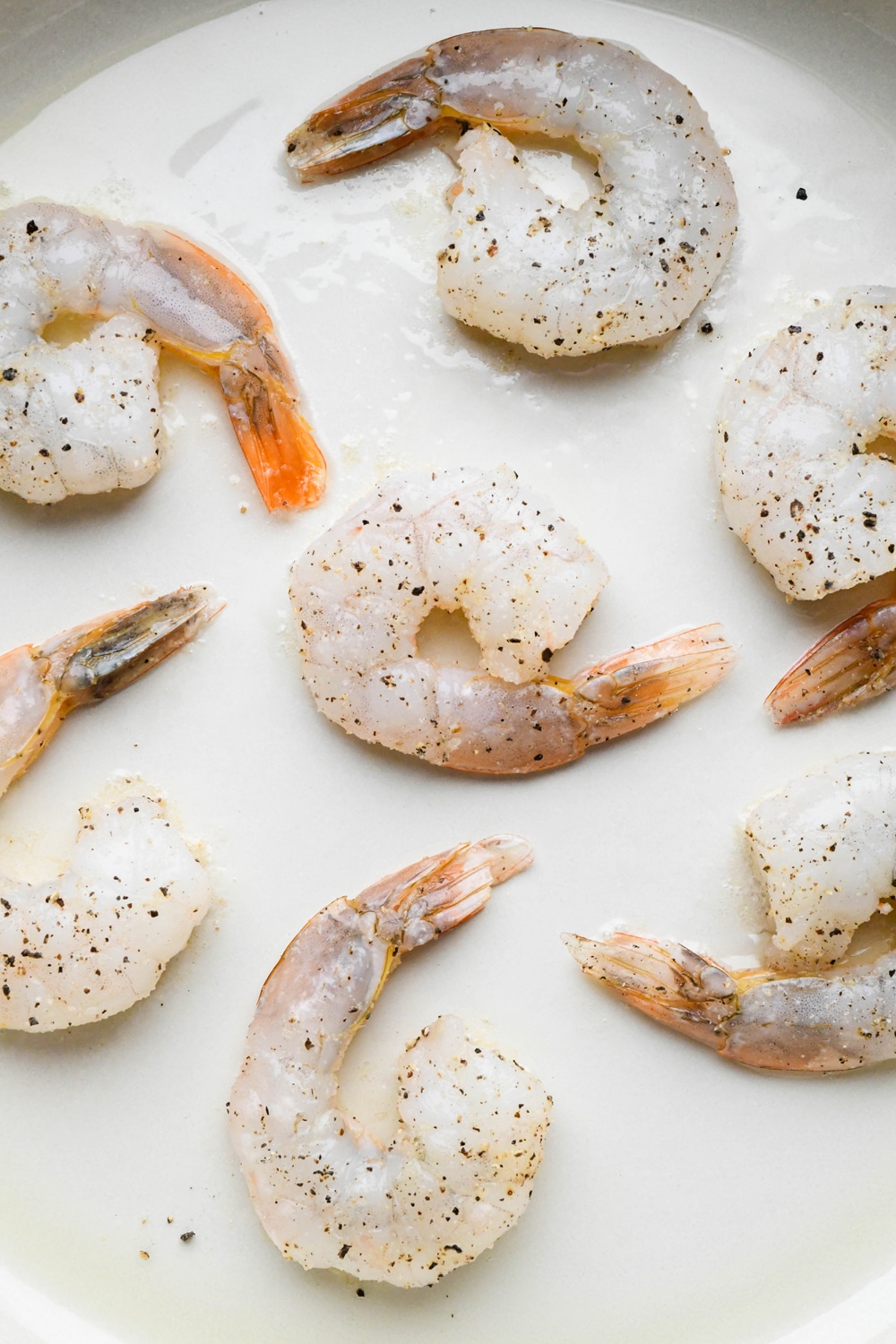 How to make Pan Seared Shrimp: Raw seasoned shrimp in a enameled cast iron skillet.