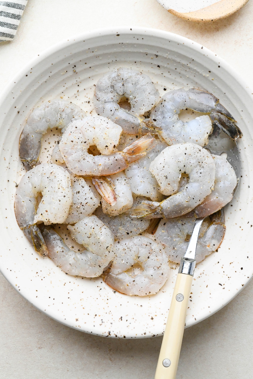How to make Pan Seared Shrimp: Raw shrimp in a large shallow bowl tossed with seasoning blend.