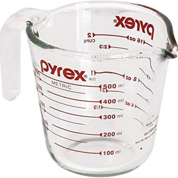 A clear glass Pyrex measuring cup with a handle and spout, marked with red metric and cup measurements up to 500 ml and 2 cups. The Pyrex logo is visible on the side.