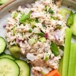 A scoop of healthy tuna salad on a plate with cut veggies.