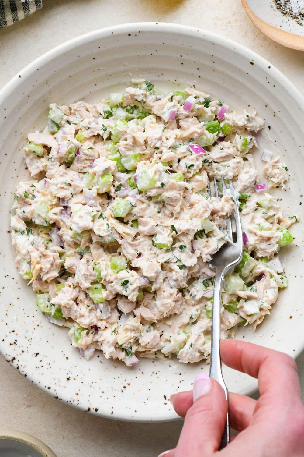How to make tuna salad: All ingredients for tuna salad mixed together in a large bowl.