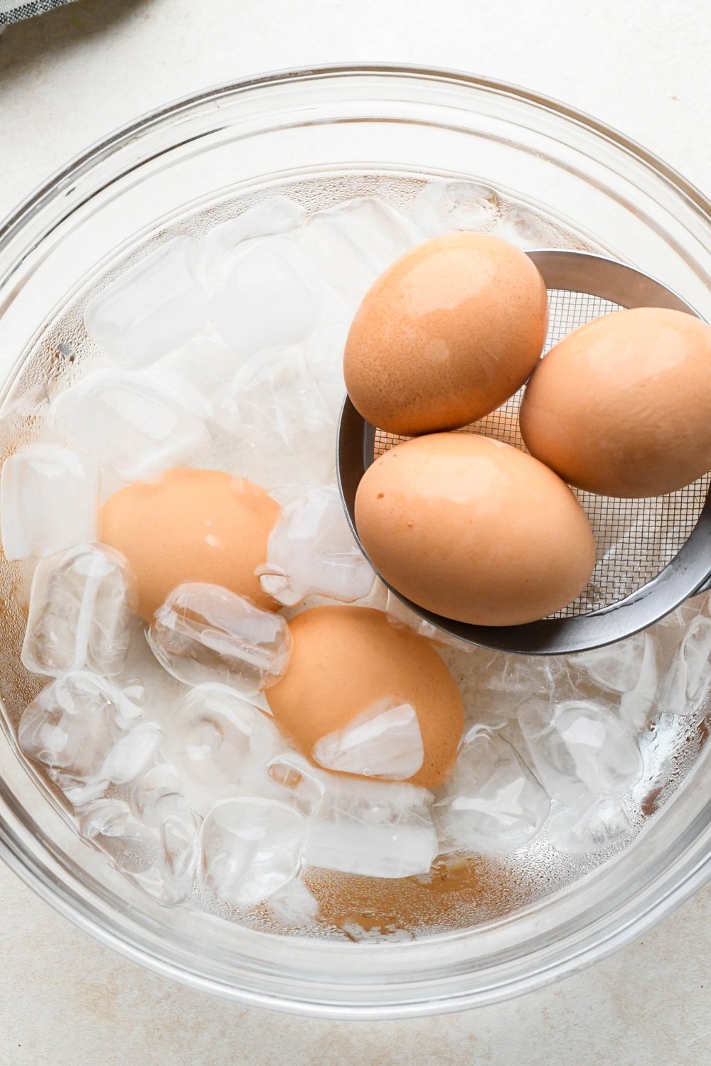 How to make deviled egg salad: Lowering hard boiled eggs into an ice water bath. 