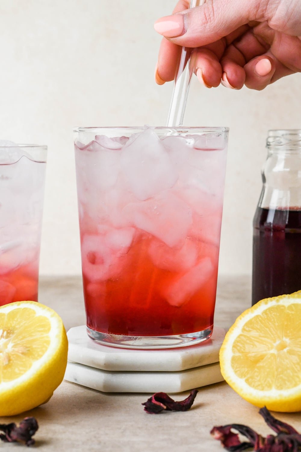 How to make hibiscus lemonade: Stirring hibiscus lemonade together with a glass straw.