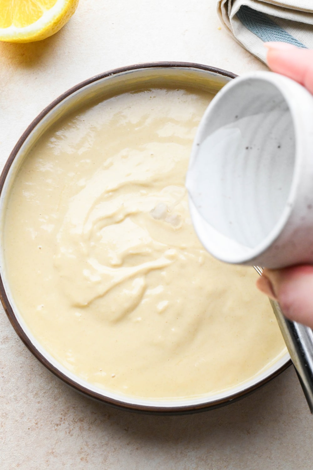 How to make tahini dressing: Pouring a little extra water into tahini dressing.