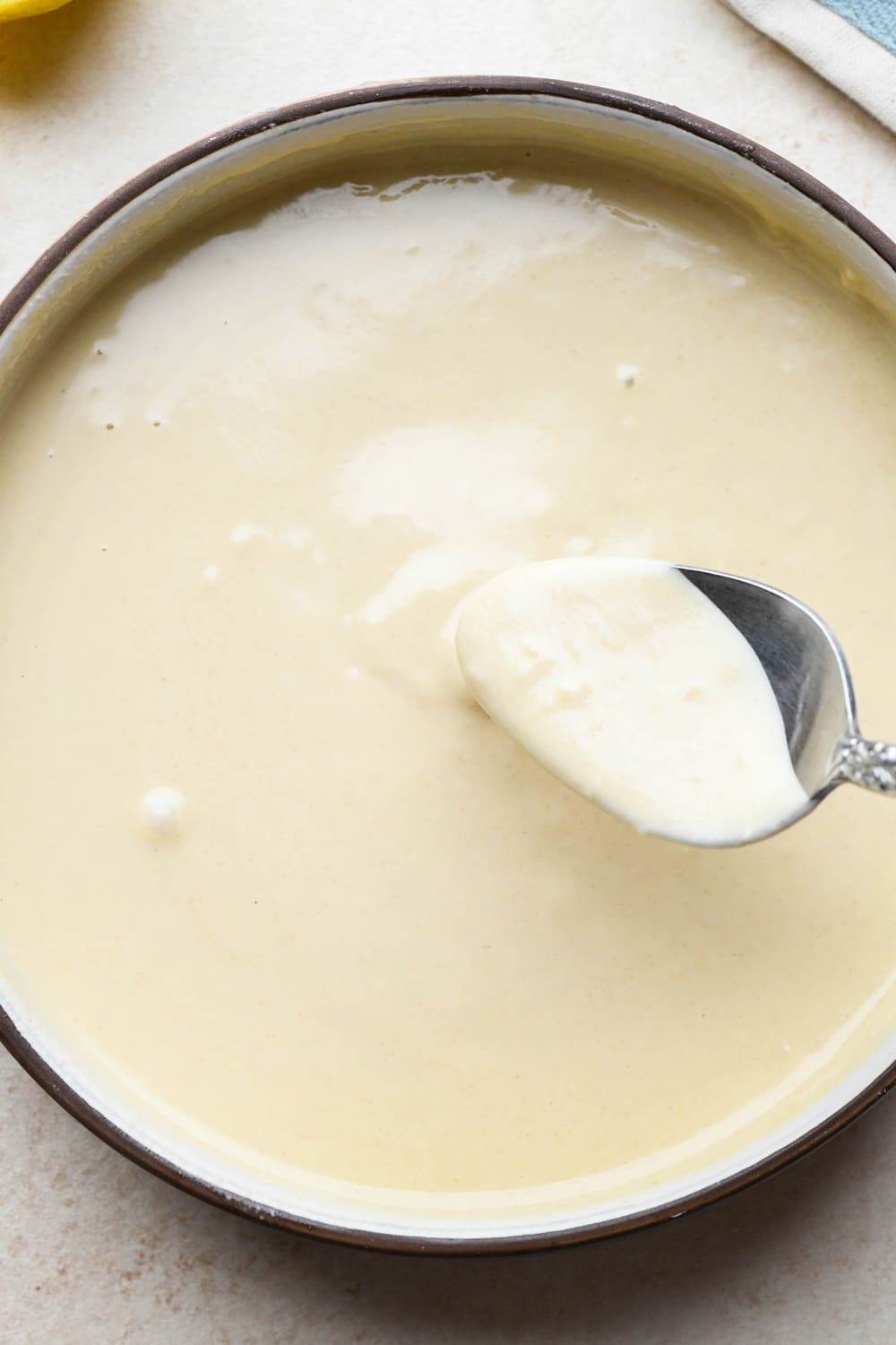How to make tahini dressing: A spoon lifting out a spoonful of dressing from the bowl to show the texture.