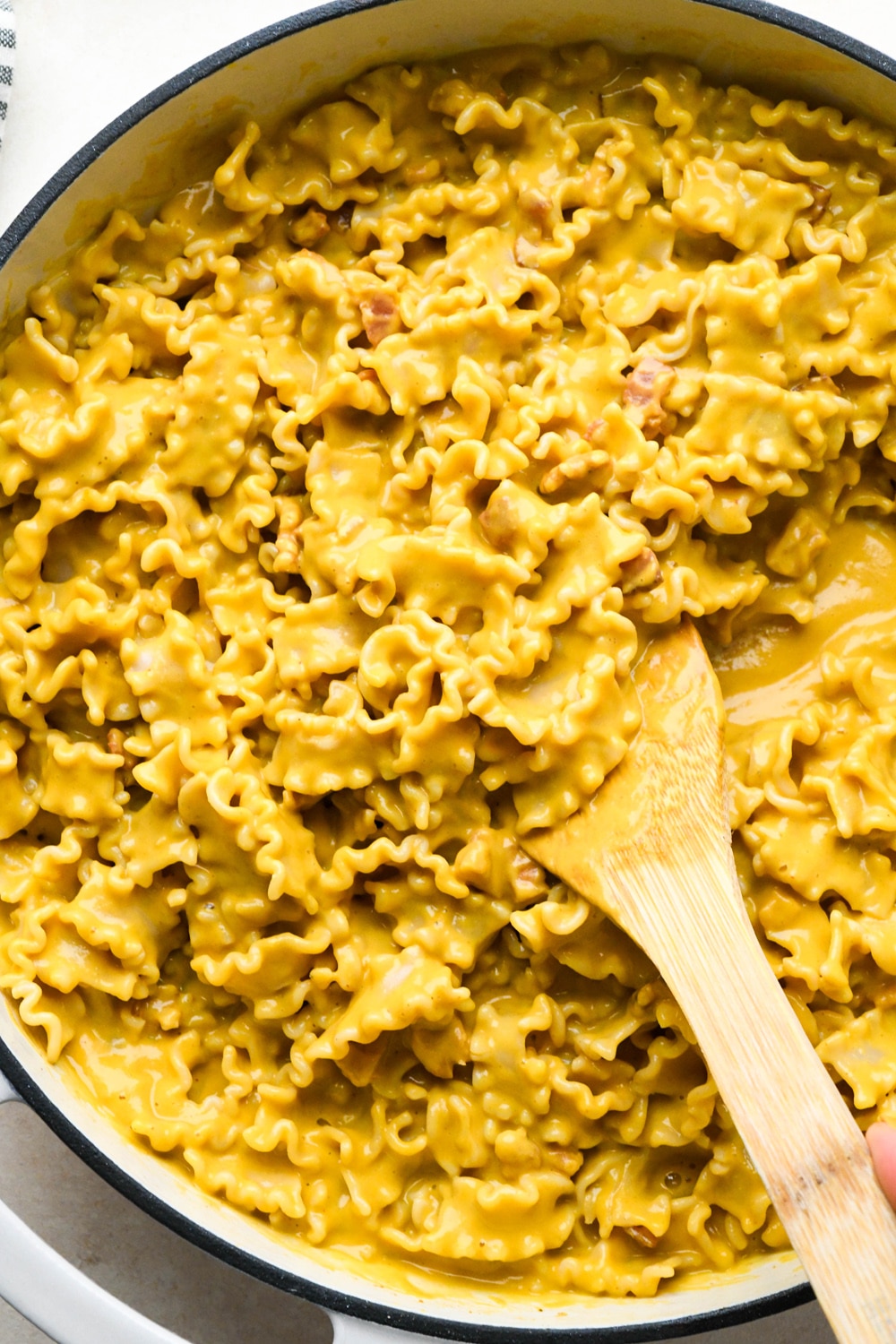 How to make Dairy Free Butternut Squash Pasta: Wooden spatula lifting out a portion of the butternut squash pasta to show the creamy, rich texture.