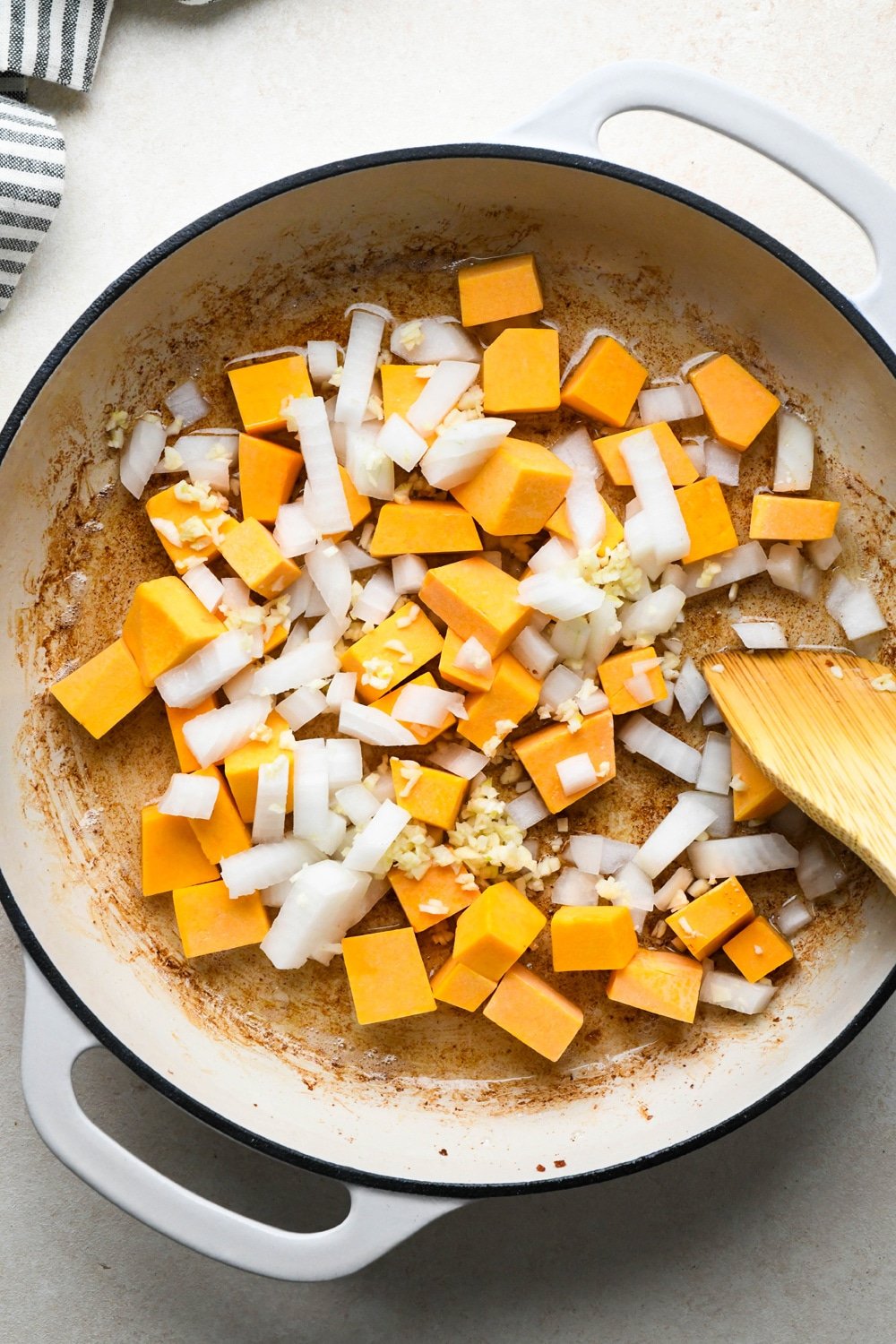 How to make Dairy Free Butternut Squash Pasta: Diced butternut squash, onion, and garlic in skillet with leftover bacon grease before sautéing. 