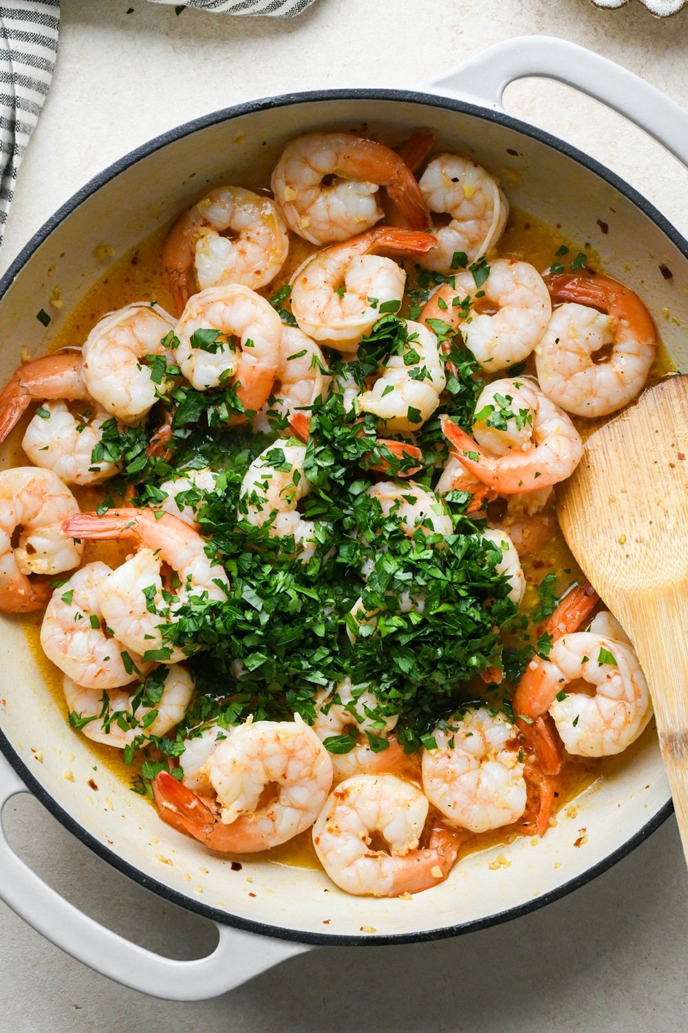 How to make Shrimp Scampi Without Wine: Fresh parsley scattered on top of cooked shrimp, before stirring to combine.
