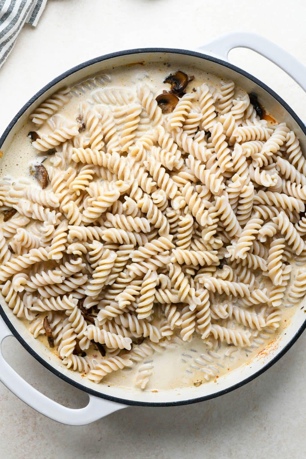 How to make Dairy Free Beef Stroganoff: Cashew cream sauce in the skillet with pasta components before stirring together.