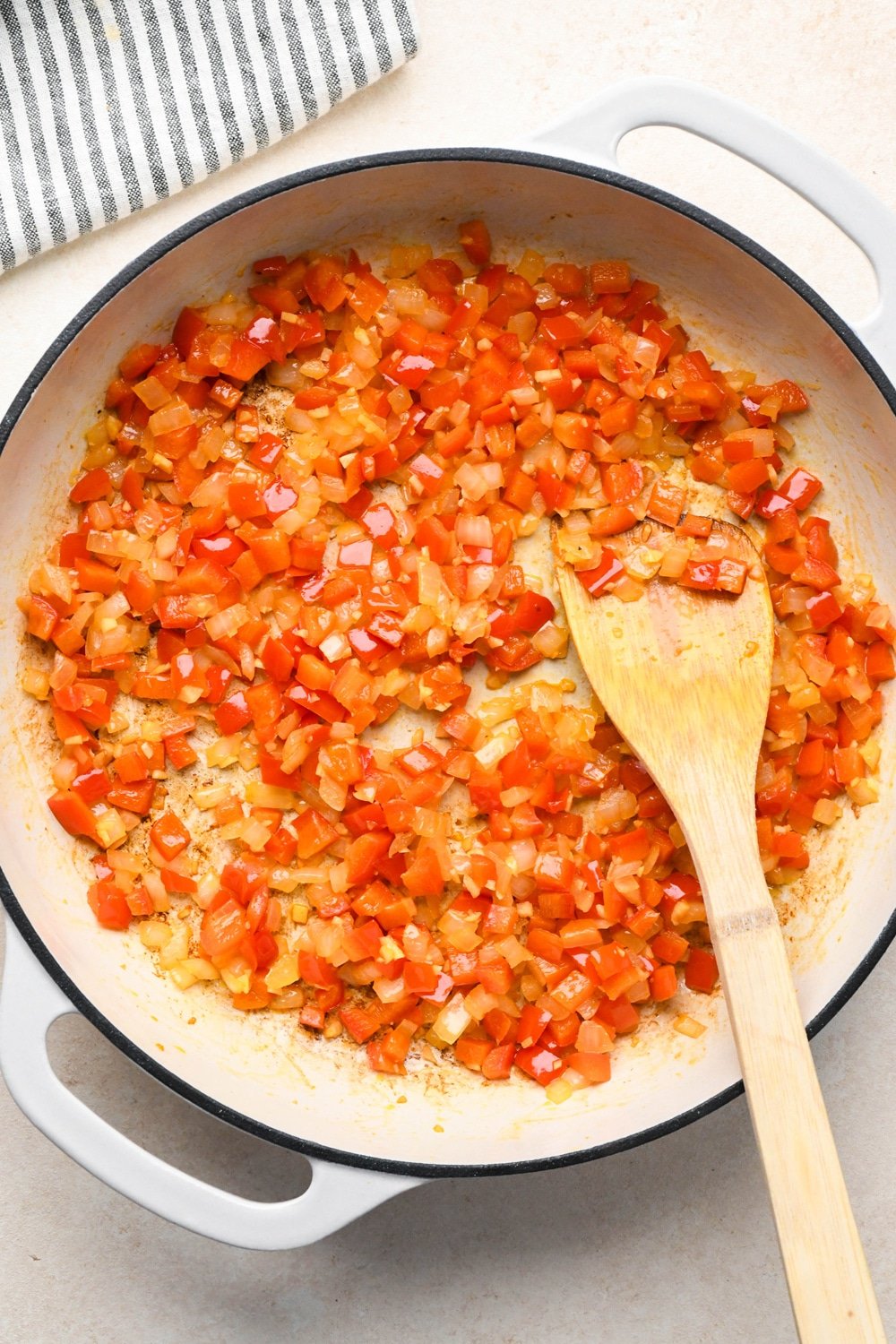How to make curry chicken and rice: Raw diced red bell pepper, onions, and chopped garlic in a skillet with olive oil after sautéing to caramelize. 