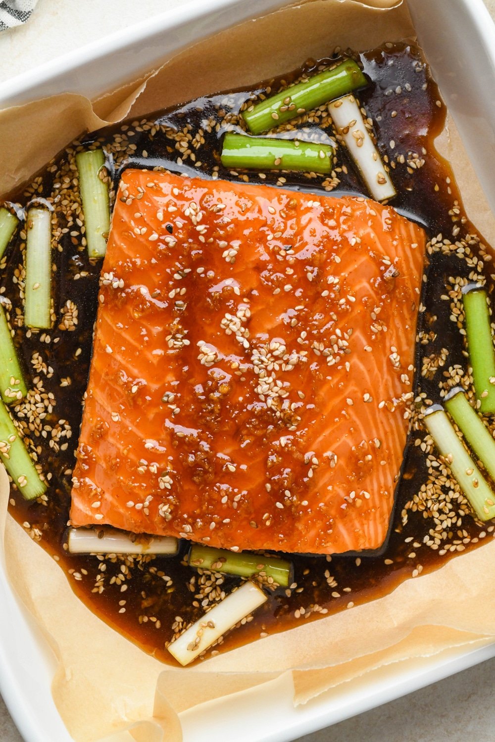 How to make garlic ginger salmon: Sauce poured over the salmon filet in baking dish.