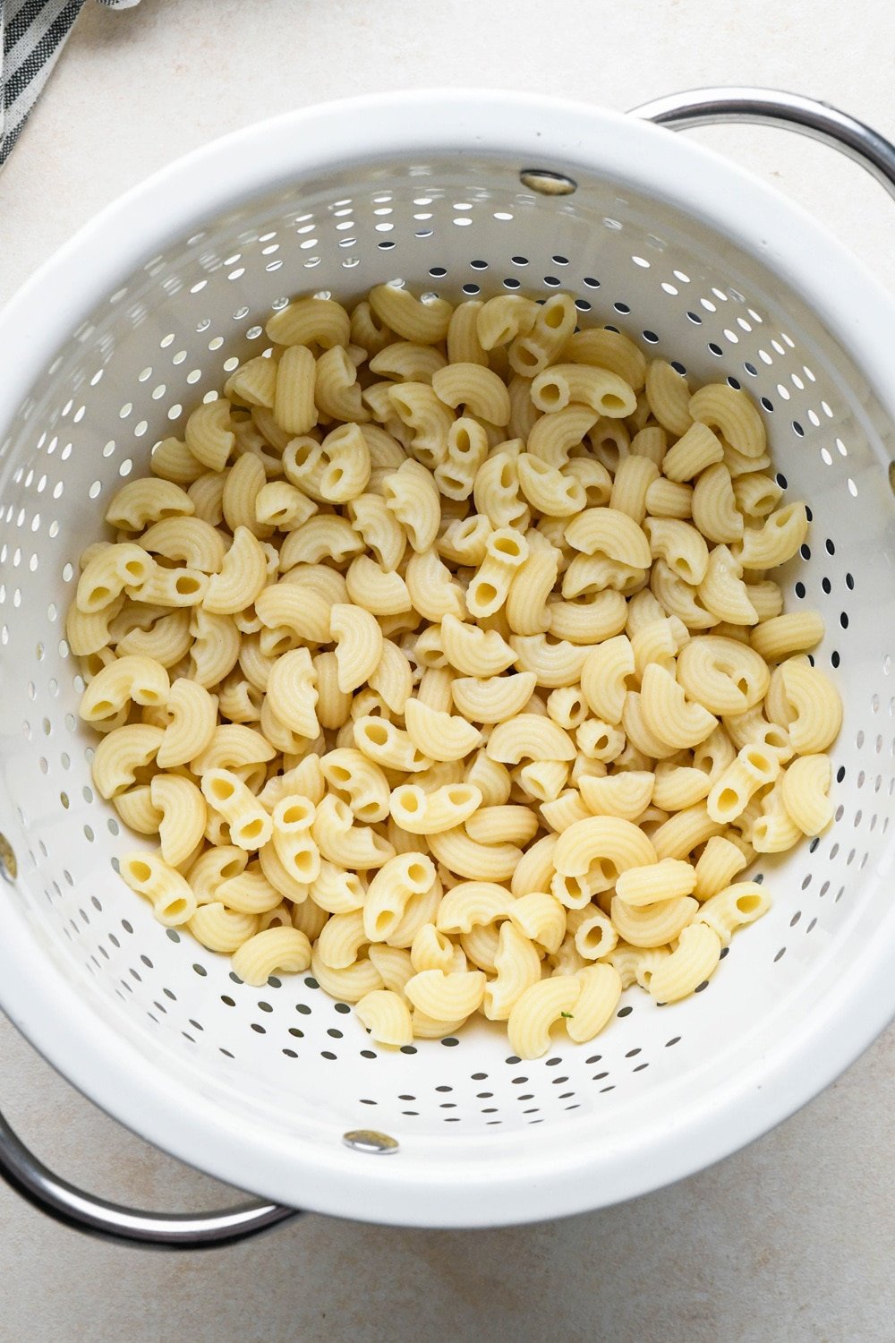 How to make Gluten Free Minestrone Soup: Cooked gluten free macaroni pasta in a white strainer.