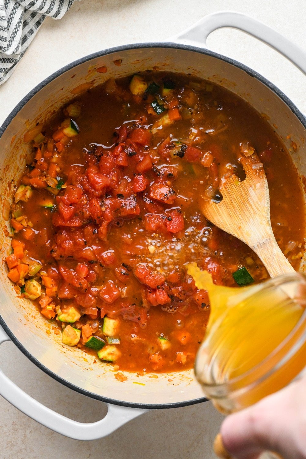 How to make Gluten Free Minestrone Soup: Fire roasted diced tomatoes added to the pot and broth being poured in.