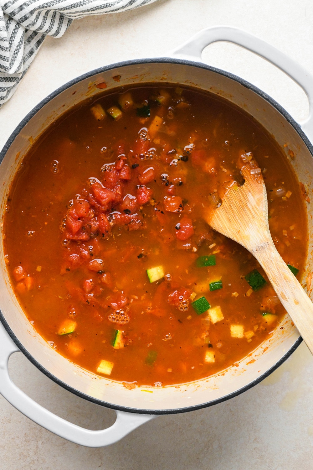 How to make Gluten Free Minestrone Soup: Broth and diced fire roasted tomatoes in the soup pot with other soup ingredients before simmering.