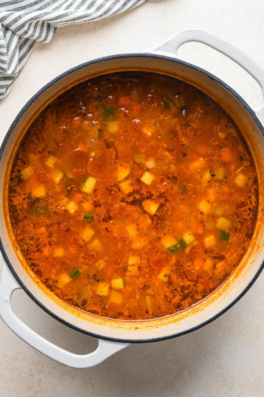 How to make Gluten Free Minestrone Soup: Broth and diced fire roasted tomatoes in the soup pot with other soup ingredients after simmering.