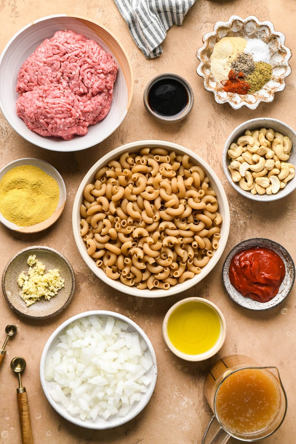 Ingredients for dairy free hamburger helper in various ceramics on a light brown speckled surface.