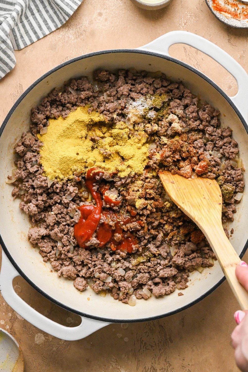 How to make dairy free hamburger helper: Cooked ground beef with onions and garlic in large ceramic coated cast iron skillet with spices, nutritional yeast, coconut aminos, and tomato paste added.