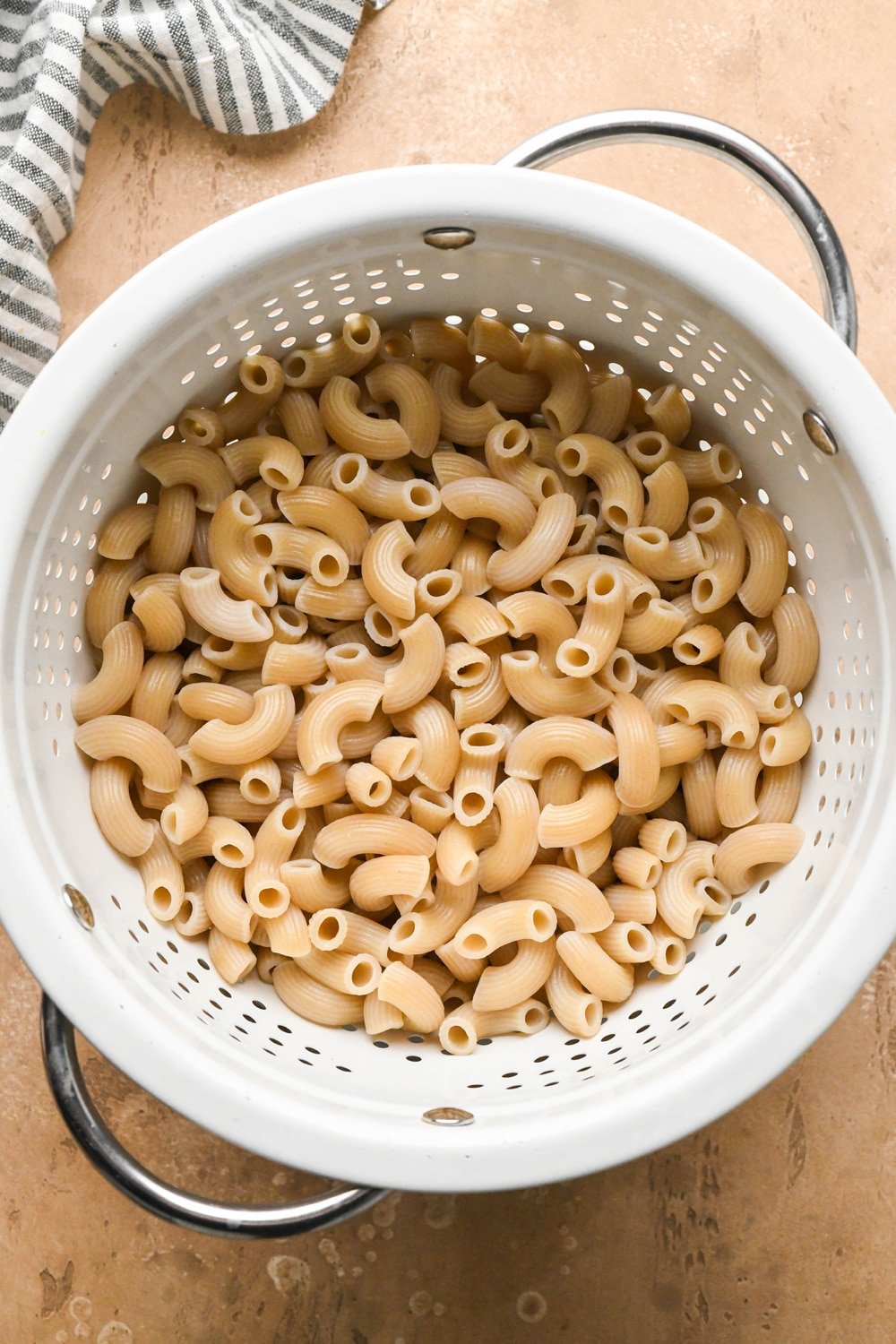 How to make dairy free hamburger helper: Cooked gluten free macaroni pasta drained in a white colander.