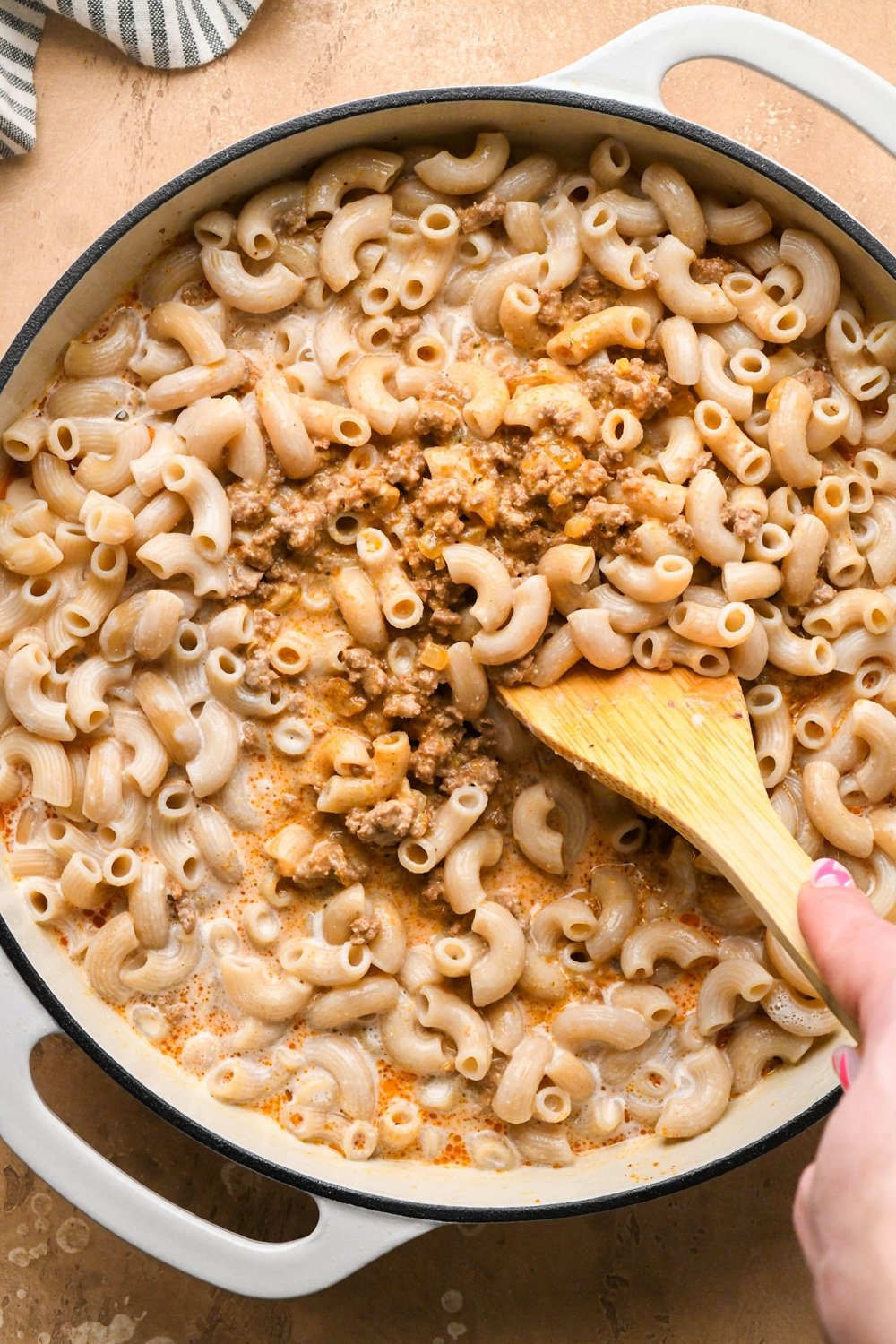 How to make dairy free hamburger helper: A wooden spatula stirring together pasta, ground beef mixture, and cashew cream sauce. 