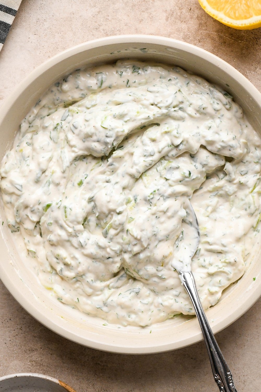 How to make dairy free tzatziki: Tzatziki all stirred together in shallow cream colored bowl, before chilling.