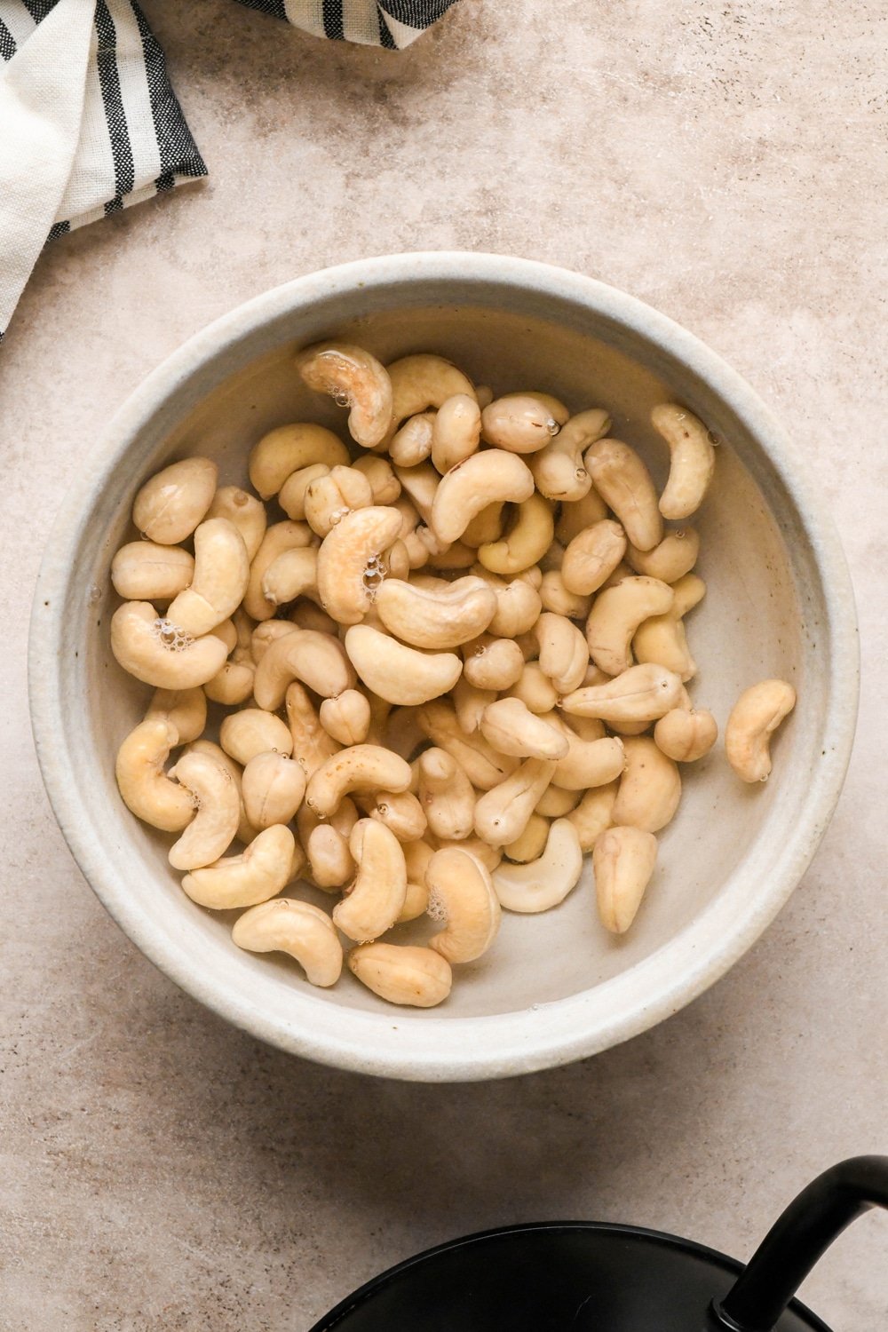 How to make dairy free tzatziki: Raw cashews in a grey ceramic bowl after just covering with boiled water to soak.