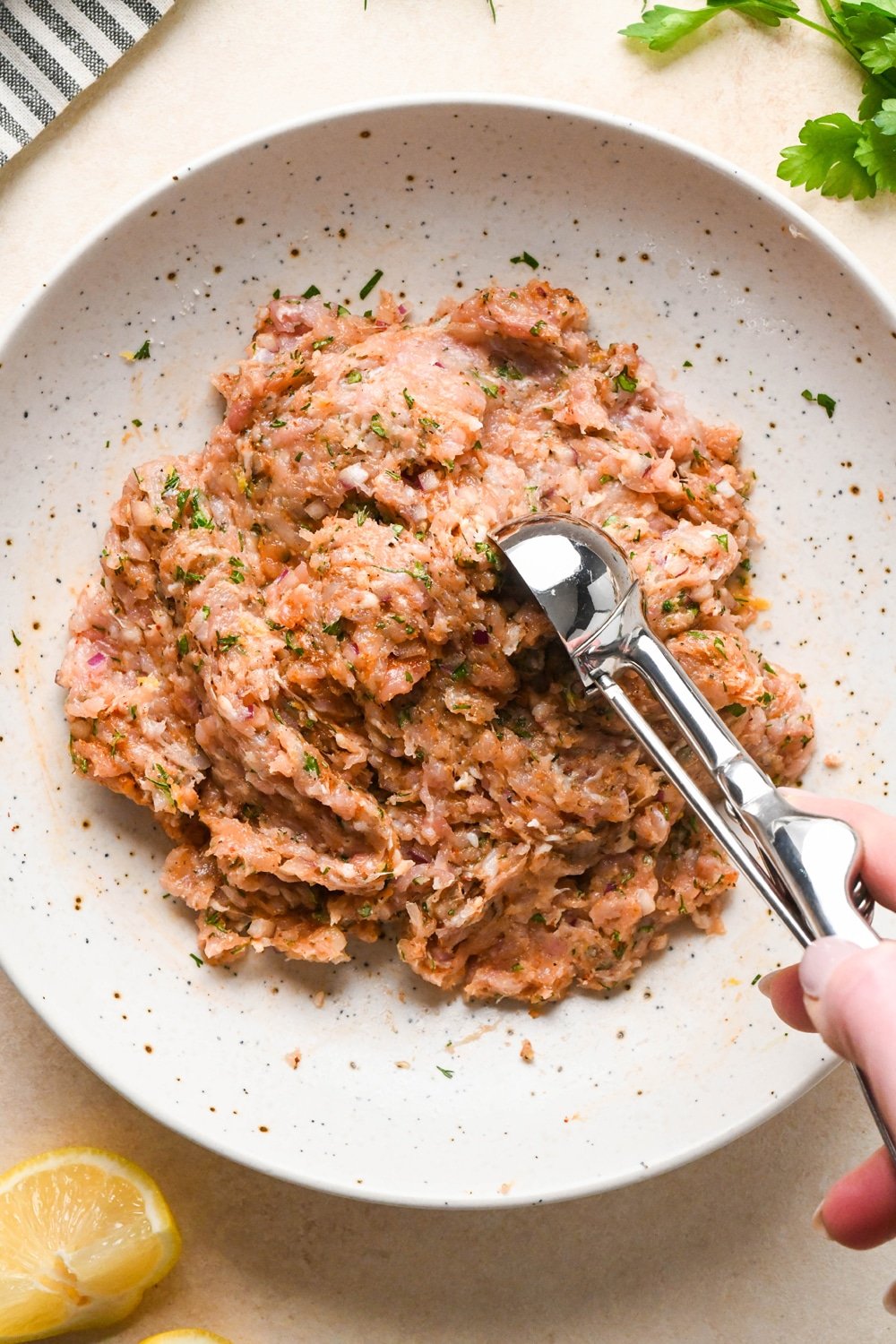 How to make Greek chicken meatballs: A cookie scoop portioning meatball mixture out of the bowl that it was mixed together in. 