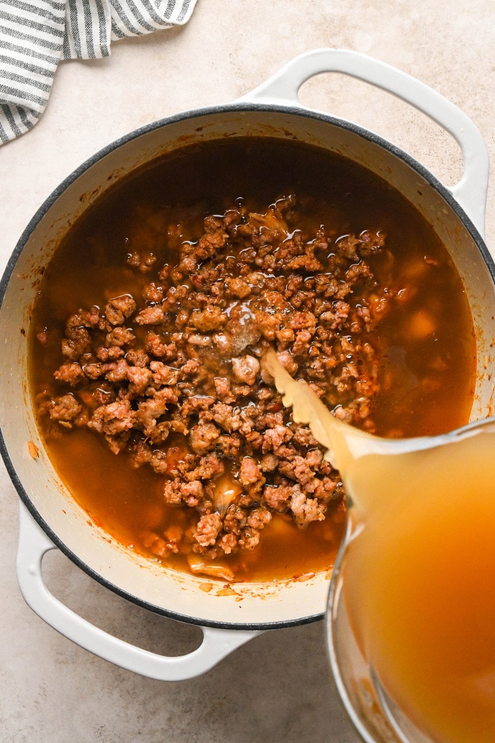 How to make Brothy Sausage and Potato Soup with Kale and Cabbage: Pouring broth into the pot.