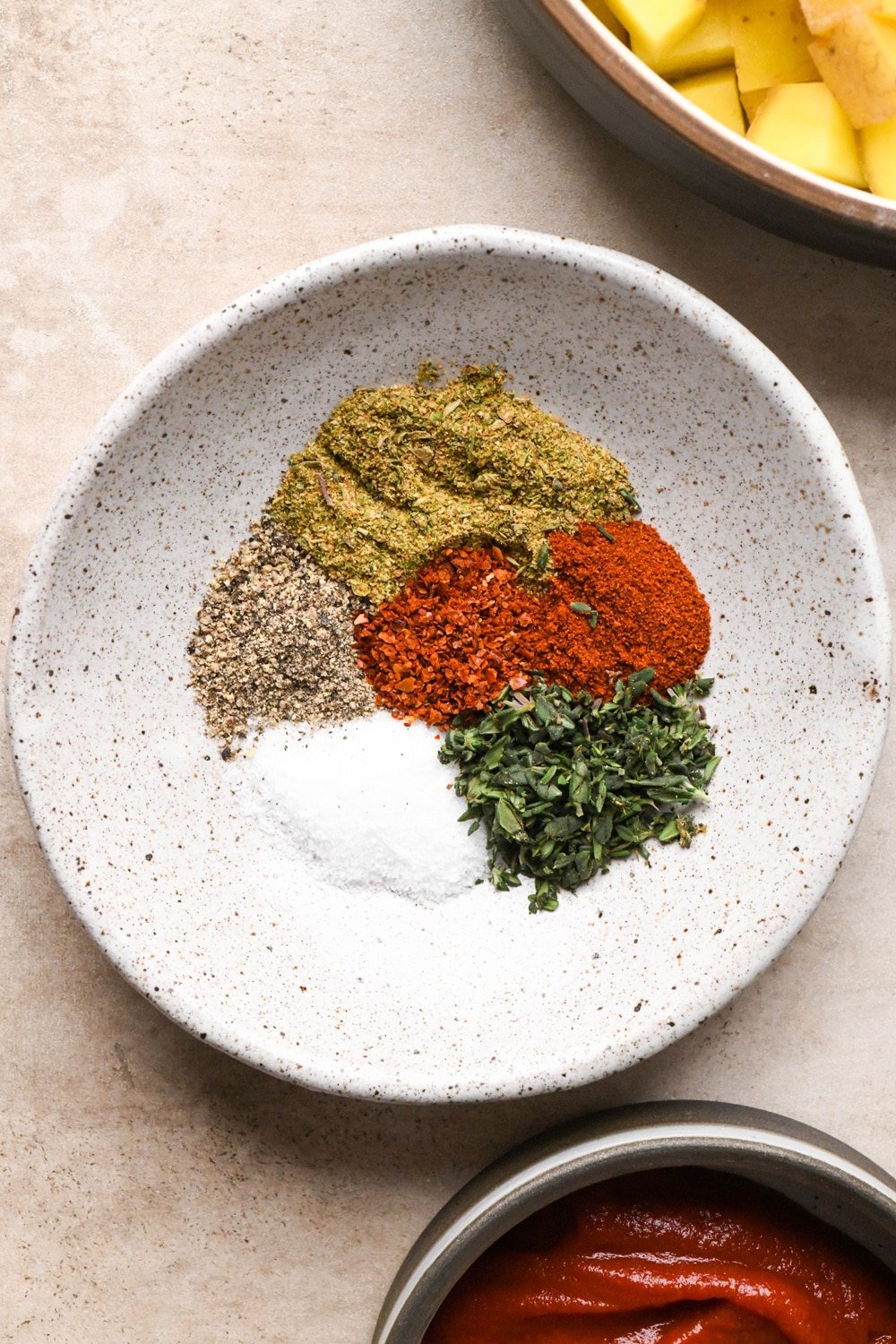 Spices and chopped fresh thyme for soup in a small ceramic white speckled dish 