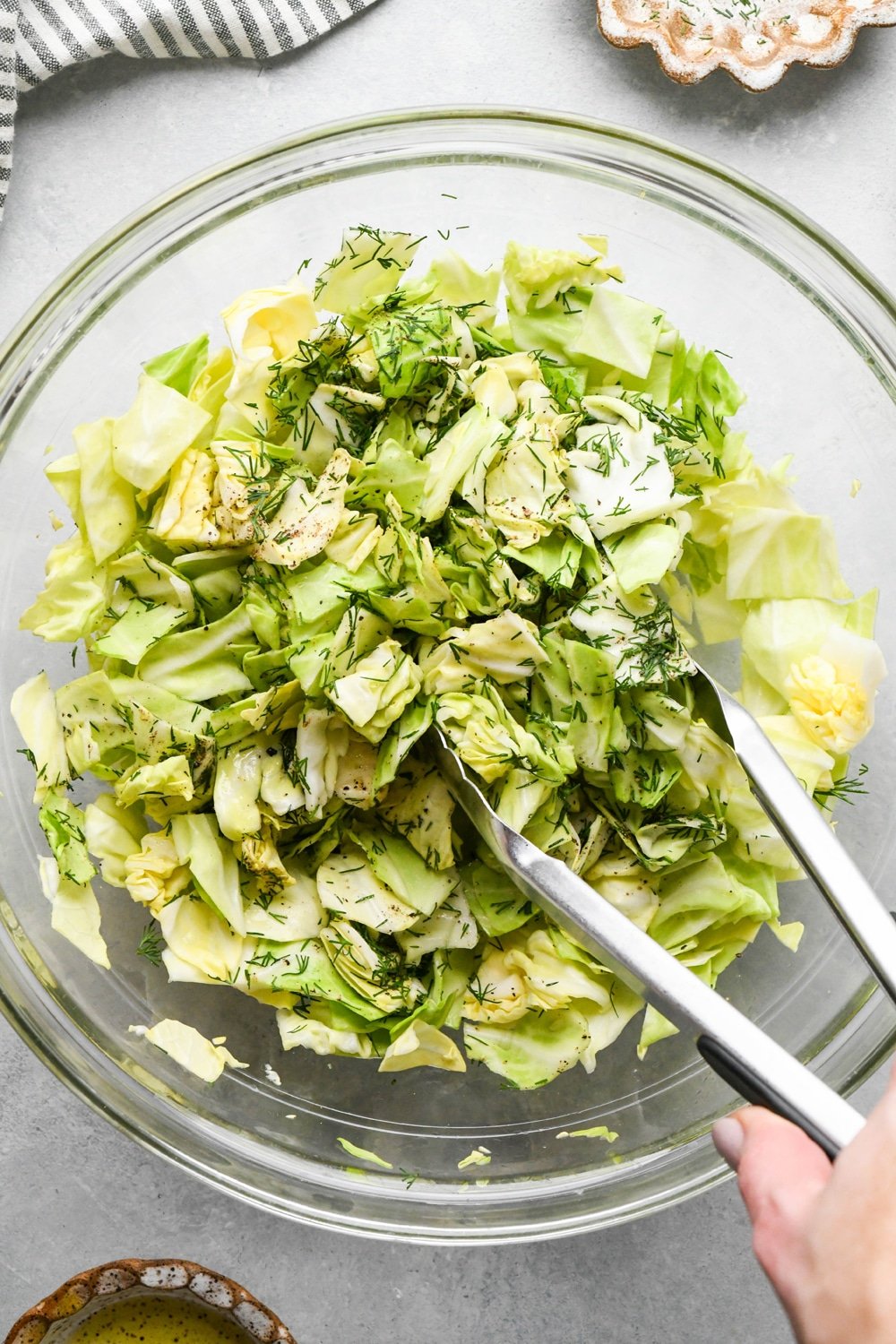 How to make chopped green cabbage salad: Using tongs to toss together the cabbage salad.